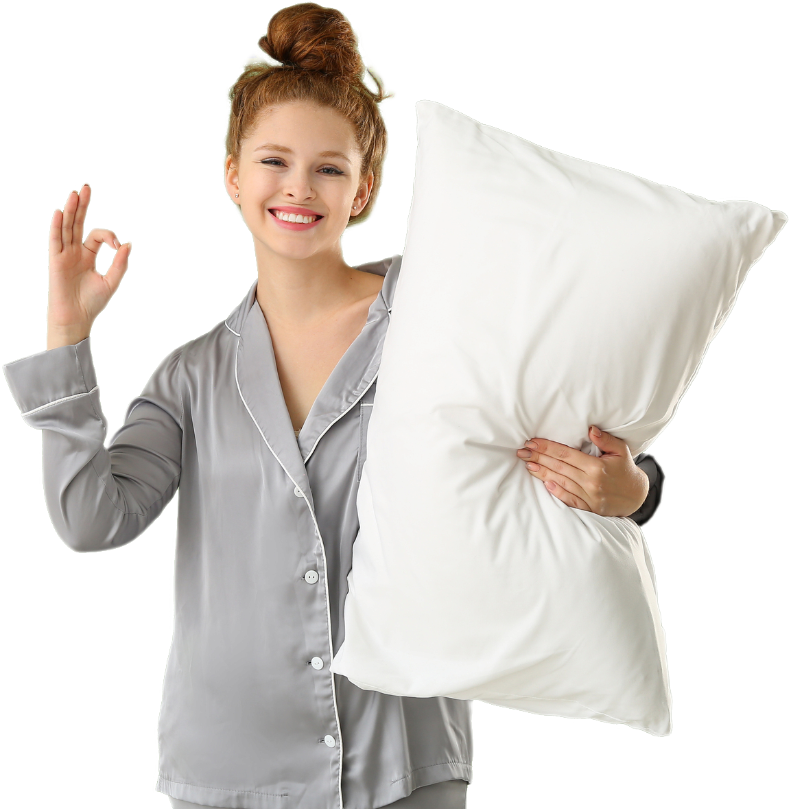 Person in gray pajamas holding a white pillow, making an “OK” gesture with one hand.